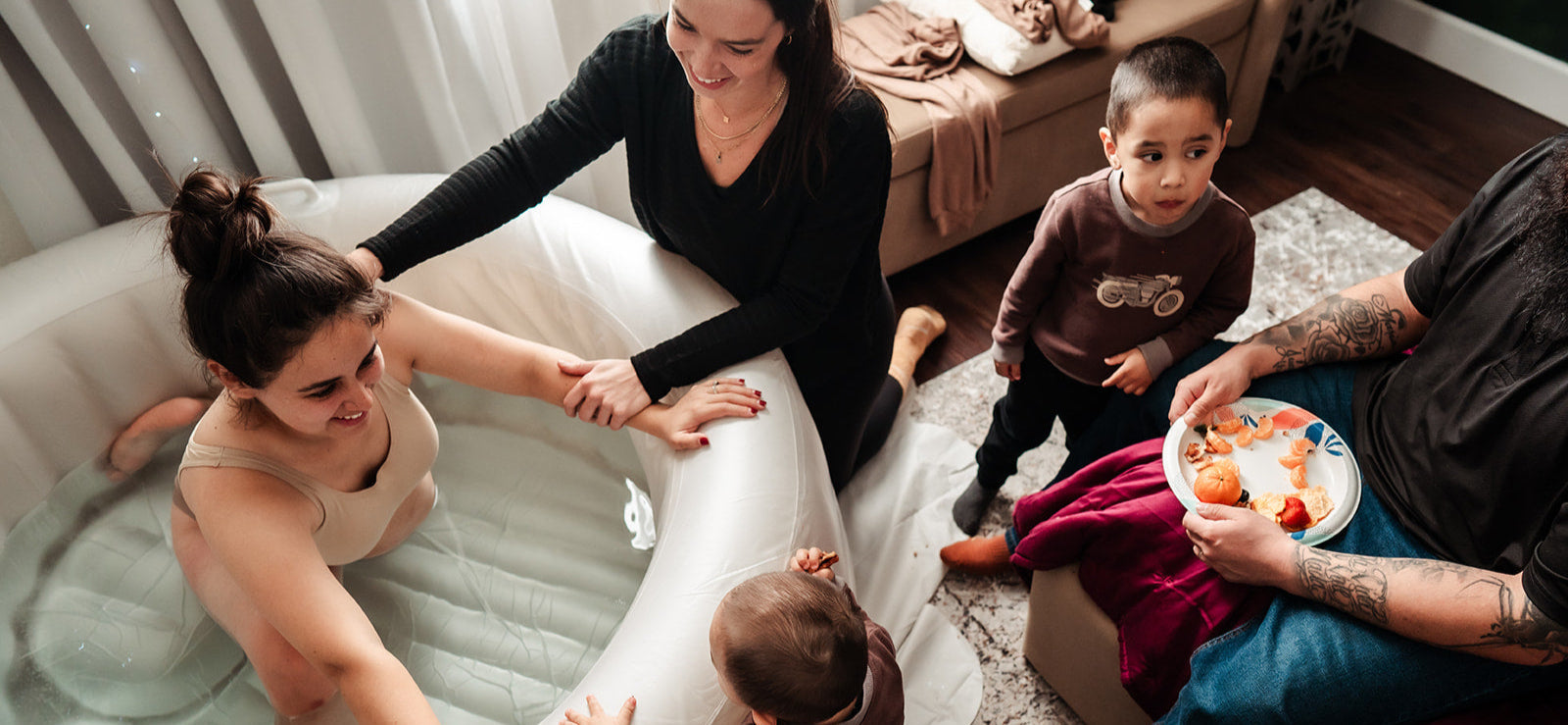 Birthing person in a tub during water birth, supported by doula